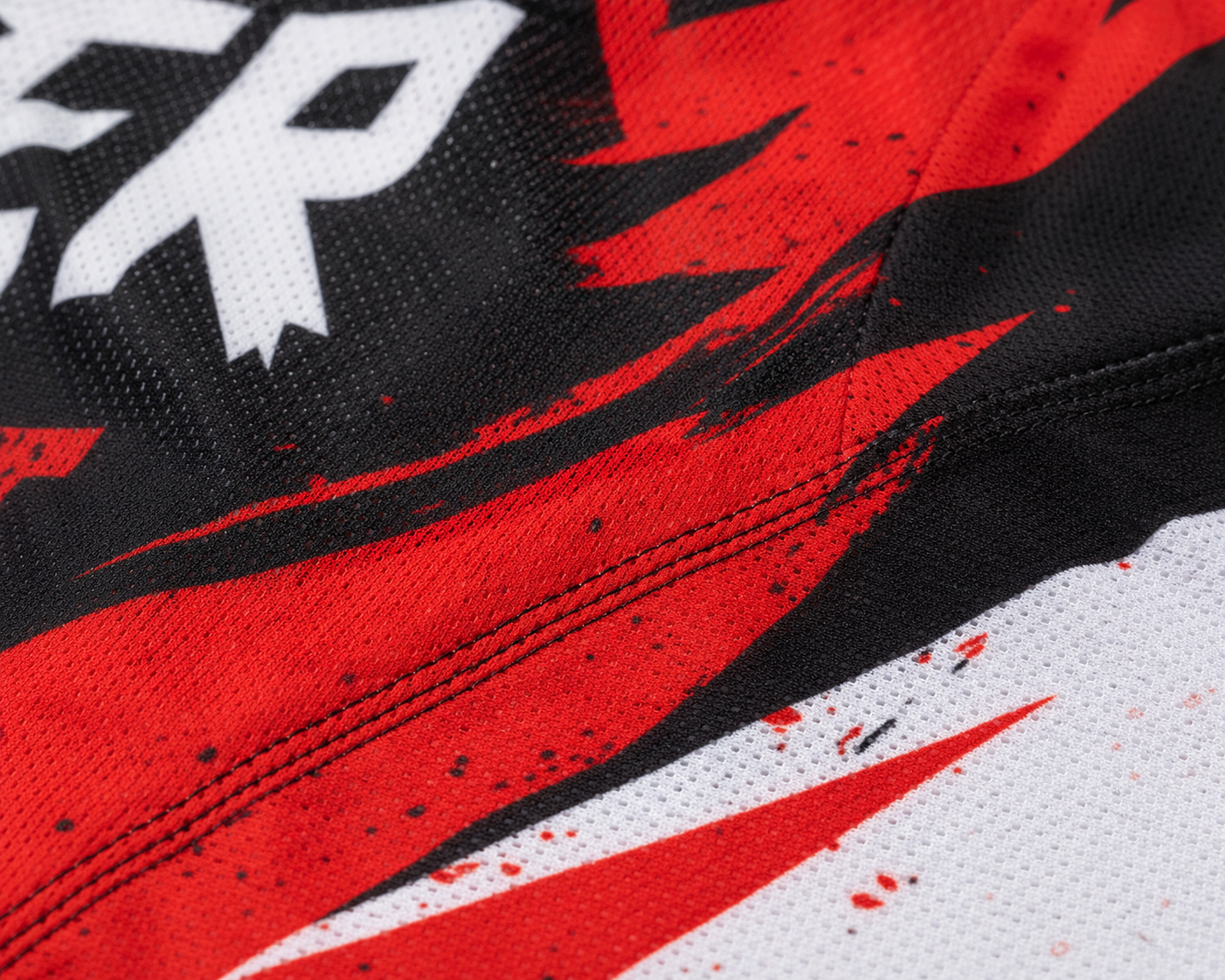Close-up of breathable mesh motocross jersey fabric with dye-sublimation printing and reinforced stitching — ZAB Sports Apparel manufacturing detail